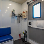 Medical site of a blood collection with blue seat, door with window, and equipment on the wall