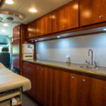 Interior view of a primary healthcare motor coach with counters, cabinets, bed, and two seats
