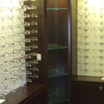 Vision clinic interior with glass frame displays, shelves, and mirrors