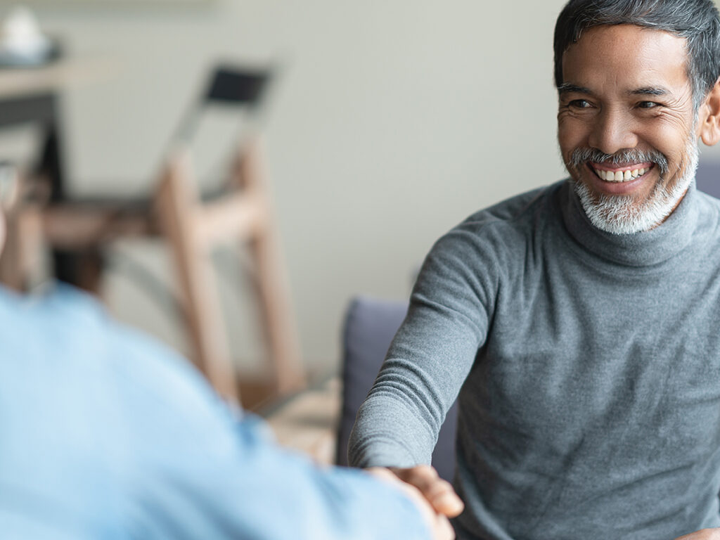 Image of a smiling man shaking hands with another after making an agreement.