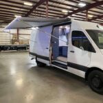 Front three-quarter view of white Sprinter specialty vehicle with side awning extended