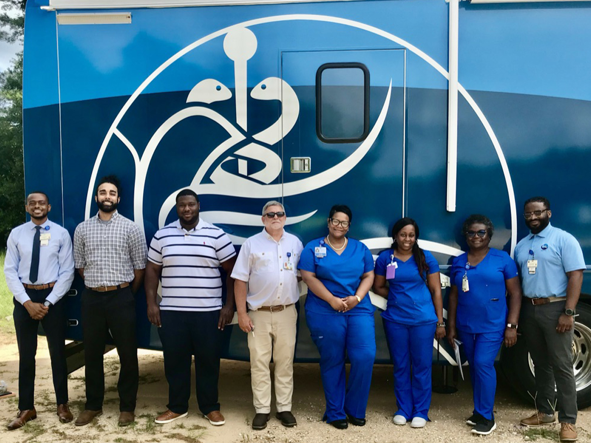 A group of healthcare workers standing in front of a PHC vehicle