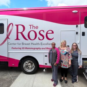 Three female nurses standing by The Rose mobile mammography clinic