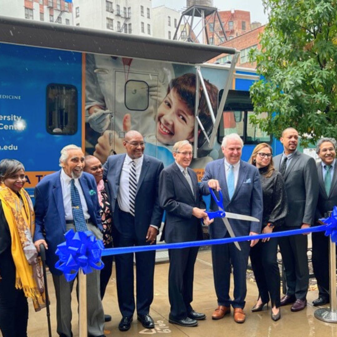 cutting ribbon in front of mobile medical vehicle